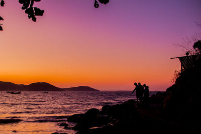 Silhouette people by sea against clear purple sky during sunset