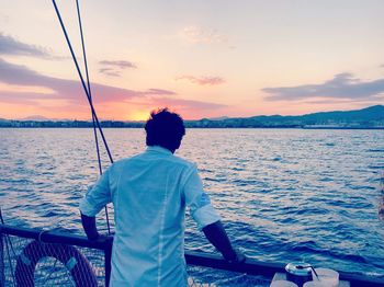 Rear view of man looking at sea against sky