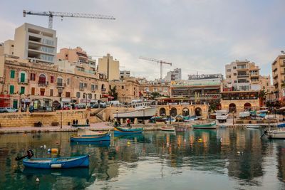 Boats moored in river against buildings in city