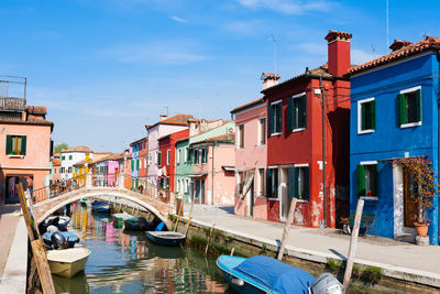 Boats moored in canal by buildings against sky in city