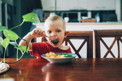 Portrait of boy eating food on table