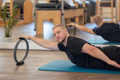 Male fitness pilates trainer shows exercises on special simulators. rubber rings for stretching