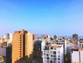 Buildings in city against clear blue sky