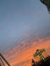 Low angle view of text and building against sky during sunset
