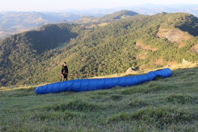 High angle view of man paragliding on grassy mountain
