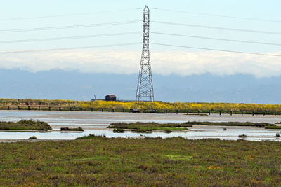 Electricity pylon on field against sky