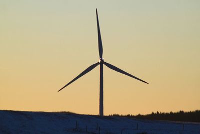 Windmill on landscape against clear sky during sunset