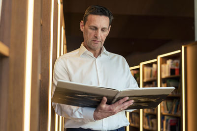 Man reading magazine in illuminated library