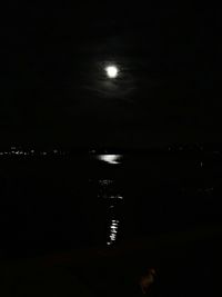 Illuminated lights on beach against sky at night