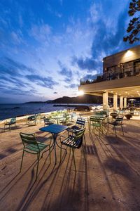 View of outdoor seating area at sea against cloudy sky