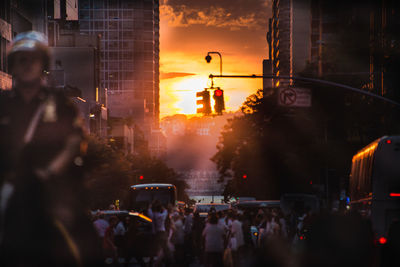 People on street in city against sky during sunset