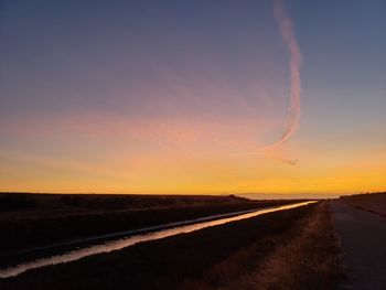 Road amidst silhouette landscape against sky during sunset