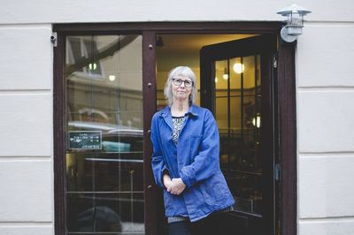 Portrait of confident female owner standing at doorway of jewelry store