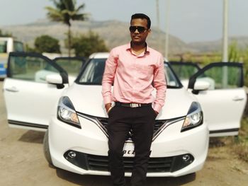 Man wearing sunglasses standing by car