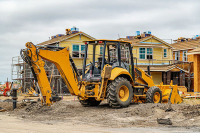 Excavator at construction site. frame houses with sip panels in background.