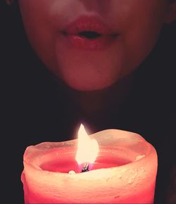 Close-up of lit candle against black background