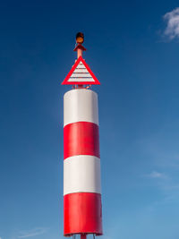 Red and white beacon at the harbour shot against the sky