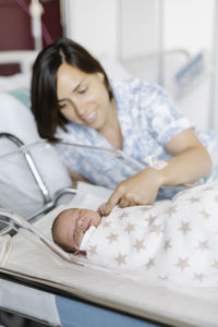 Woman with sleeping newborn baby in hospital