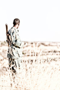 Rear view of man standing on field against clear sky