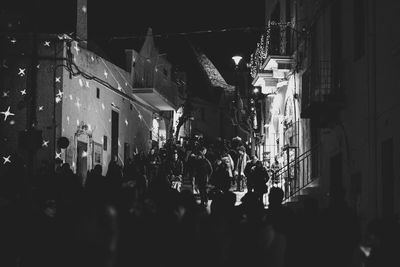 People on street amidst buildings in city at night