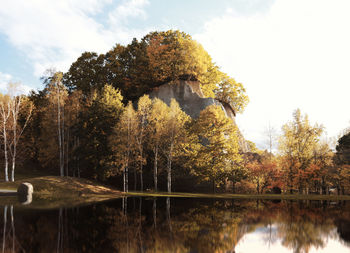 Trees by lake against sky during autumn