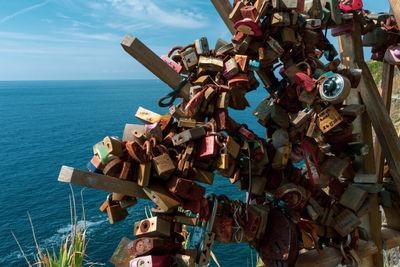 Padlocks on railing by sea against sky