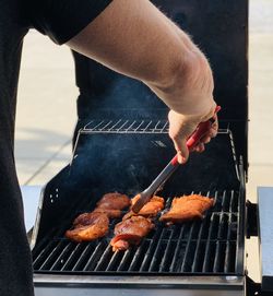 Midsection of man preparing food on barbecue grill