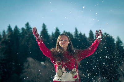 Smiling girl throwing snow while standing outdoors