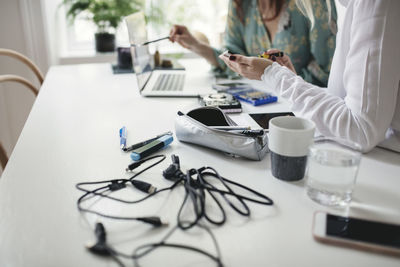 Midsection of female colleagues working on hard drive at table in home office