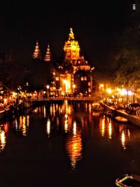 Illuminated cathedral by river against sky at night