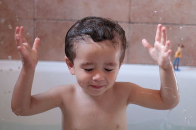 Close-up of shirtless boy enjoying in bathtub