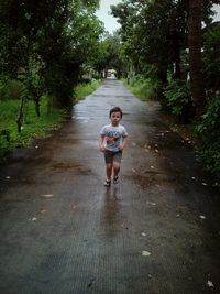 Full length of boy running on footpath amidst tree