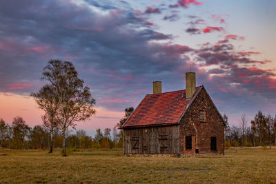 Abandoned house on field against sky during sunset