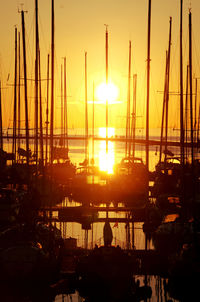 Sailboats moored on harbor against sky during sunset