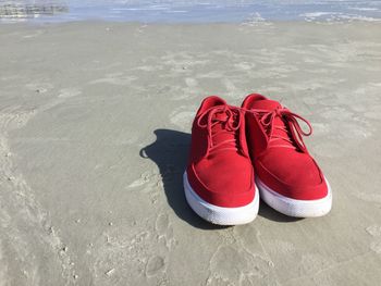 Close-up of red shoes on beach