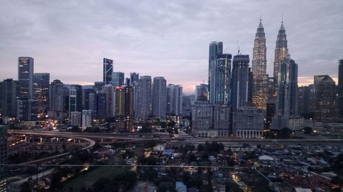 Aerial view of buildings in city against cloudy sky