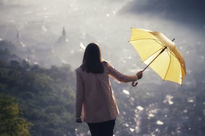 Rear view of woman holding umbrella against mountain