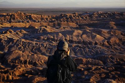 Rear view of man standing against mountains during sunset