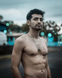 Portrait of shirtless man standing outdoors