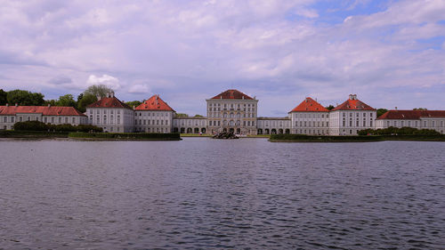 Buildings by river against sky