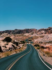 Road amidst landscape against clear blue sky