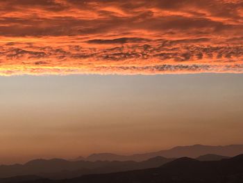 Scenic view of dramatic sky over mountains during sunset