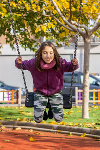 Portrait of girl in swing at playground