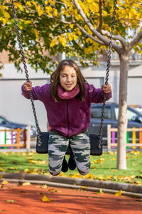 Portrait of girl in swing at playground