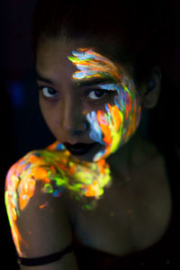 Close-up portrait of young woman with paint on face and shoulder