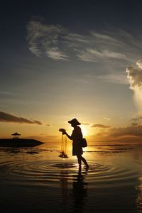 Silhouette man standing on beach against sky during sunset