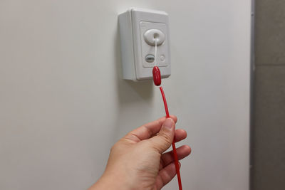 Close-up of hand holding electric lamp against wall