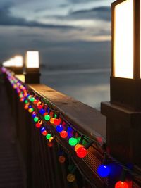 Close-up of illuminated lighting equipment hanging against sky