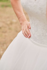 Midsection of bride with hand on hip standing outdoors