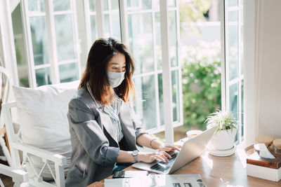 Young woman using mobile phone while sitting on table